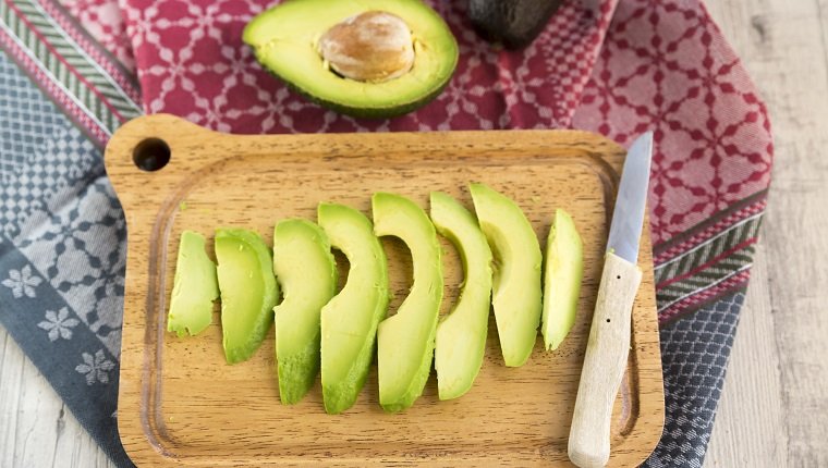 Sliced avocado and knife on chopping board