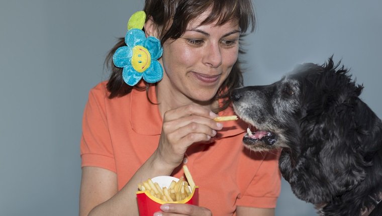 Woman eating pommes frites with her dog in Ticino Switzerland.